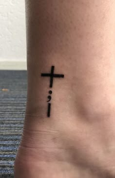 a cross tattoo on the foot of a person with no shoes in front of it