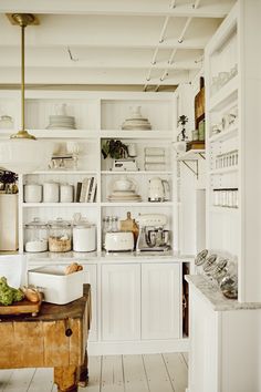 a kitchen filled with lots of white cupboards and counter top covered in pots and pans