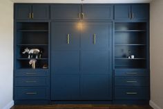 a blue bookcase with gold handles and brass knobs on the doors is in an empty room