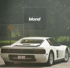 a white sports car is parked in front of a sign that reads blond on it