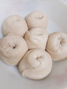 six doughnuts in a white bowl with icing on the top and bottom