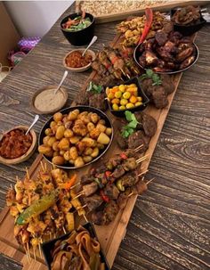 a wooden table topped with lots of different types of food on skewered skewers