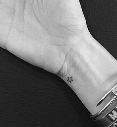 a person's wrist with a small star tattoo on it