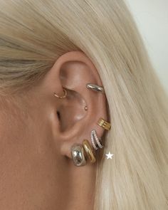 a woman with blonde hair wearing three different ear piercings