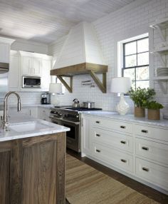 a kitchen with white cabinets and an island in front of the stove, sink and microwave