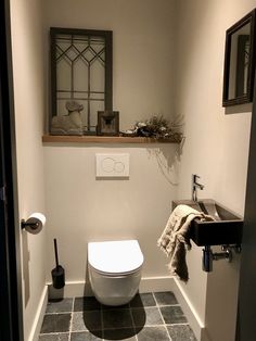 a white toilet sitting in a bathroom next to a sink under a mirror and towel rack