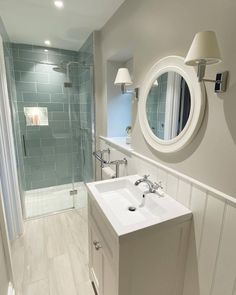 a white sink sitting under a bathroom mirror next to a walk in shower