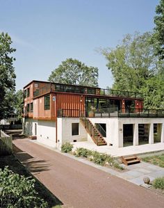 a house made out of shipping containers with stairs leading up to the second floor and upper level