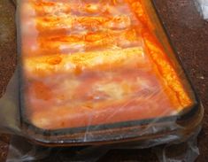 an uncooked casserole dish sitting on top of a counter covered in plastic