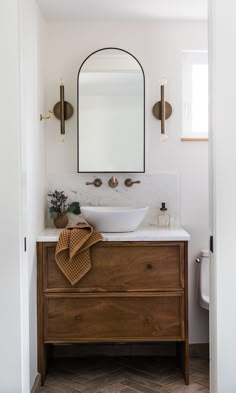 a bathroom with a sink, mirror and towel on the dresser in front of it