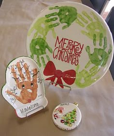 two plates with handprints on them are sitting on a table next to a christmas ornament