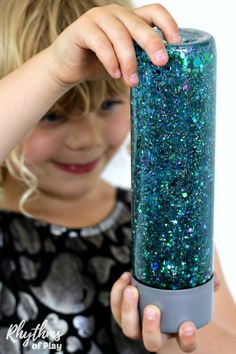 Learn how to make your own glittering mermaid tail sensory bottle! Calm down discovery jars like this glitter sensory bottle can be used for portable no mess safe sensory play, calming an overwhelmed child, and helping children learn to self-regulate. #RhythmsOfPlay #SensoryPlay #SensoryBottles #PositiveParenting #BehaviorManagement #MermaidTheme #MermaidParty #PositiveParenting #BehaviorManagement Easy Homemade Costumes, Mermaid Sensory, Sensory Bottles For Toddlers, Glitter Sensory Bottles, Calming Bottle, Calming Jar, Toddler Road Trip, Diy Mermaid Tail, Calm Down Jar