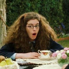 a woman sitting at a table with a tea cup in front of her