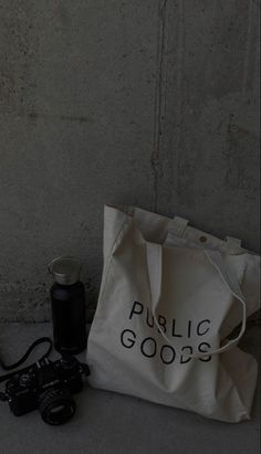 a white bag with the words public goods on it next to a pair of binoculars