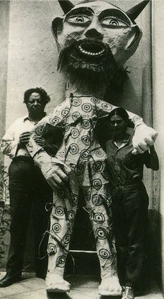 two men standing next to a statue of a man with a cat's head on it