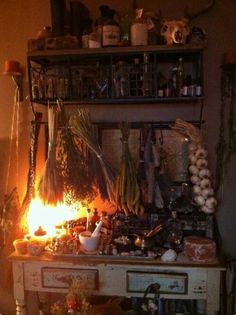 an old dresser with many items on it in front of a lit candle and shelves