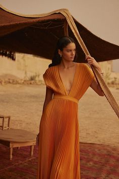 a woman in an orange dress is holding a large umbrella