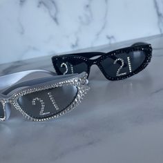 two pairs of sunglasses with the number twenty five on them, sitting on a marble surface