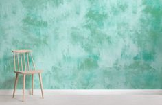 a wooden chair sitting in front of a wall with green and blue paint on it