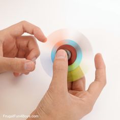 two hands are holding a colorful object in front of the other hand and touching it with their fingers