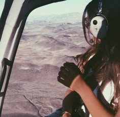 a woman is flying in an airplane with her headphones on and looking out the window