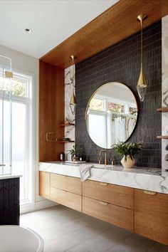 a bathroom with marble counter tops and wooden cabinets, along with a round mirror on the wall