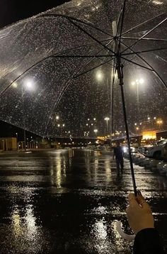 someone holding an umbrella in the rain at night