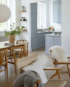 an open kitchen and dining room area with chairs, table, sink and shelves on the wall