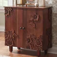 a wooden cabinet with carved flowers on the front and sides, along with a clock