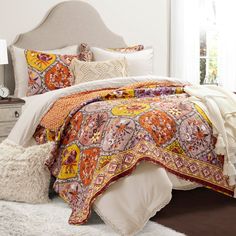 a bed with an orange, yellow and pink comforter