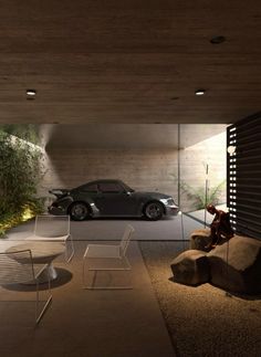 a car is parked in the garage next to two chairs and a table with a teddy bear on it