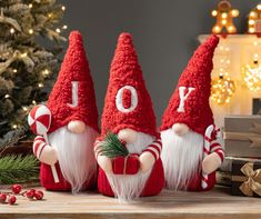 three red knitted gnomes sitting next to each other on a table with christmas decorations