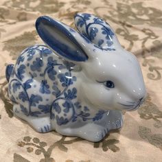 a blue and white rabbit figurine sitting on top of a floral table cloth