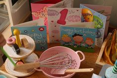 a wooden table topped with lots of greeting cards and cooking utensils on top of it