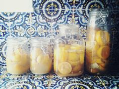 four jars filled with lemonade sitting on top of a blue and white tablecloth