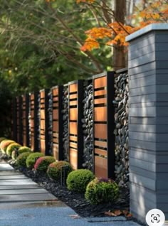 a long row of wooden fence next to a sidewalk with trees and bushes in the background