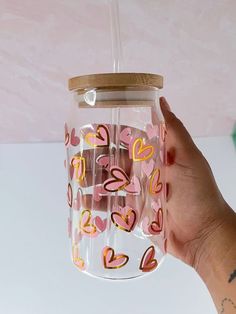 a hand holding a clear cup with hearts on it