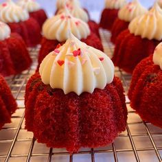 red velvet cupcakes with white frosting and sprinkles on a cooling rack