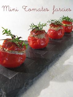 three tomatoes with herbs on them are sitting on a slate platter that says, ferments mini