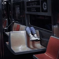 a person sitting on a subway train with their feet up and legs crossed, while the other end is empty