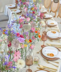 a long table is set with flowers and gold place settings for an elegant wedding reception