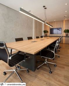 an empty conference room with black chairs and a large wooden table in the foreground