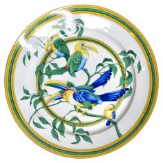 a plate with birds painted on it and green leaves around the edge, in front of a white background