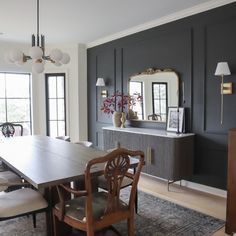 a dining room table and chairs in front of two windows with large mirrors on the wall