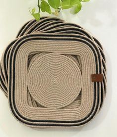 a set of four braided placemats sitting on top of each other next to a potted plant