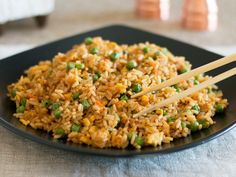 rice and peas with chopsticks on a black plate