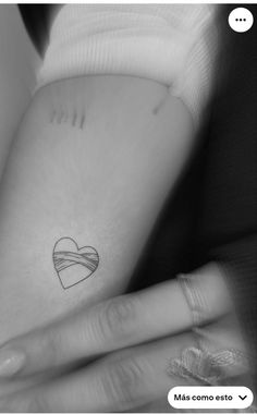 a small heart tattoo on the back of a woman's left arm and hand