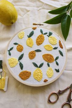 an embroidery project with pineapples and lemons on the table next to scissors