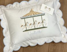 a pillow with a carousel on it and a name tag attached to the pillow cover