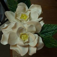 a bouquet of white flowers sitting on top of a wooden table next to someone's feet